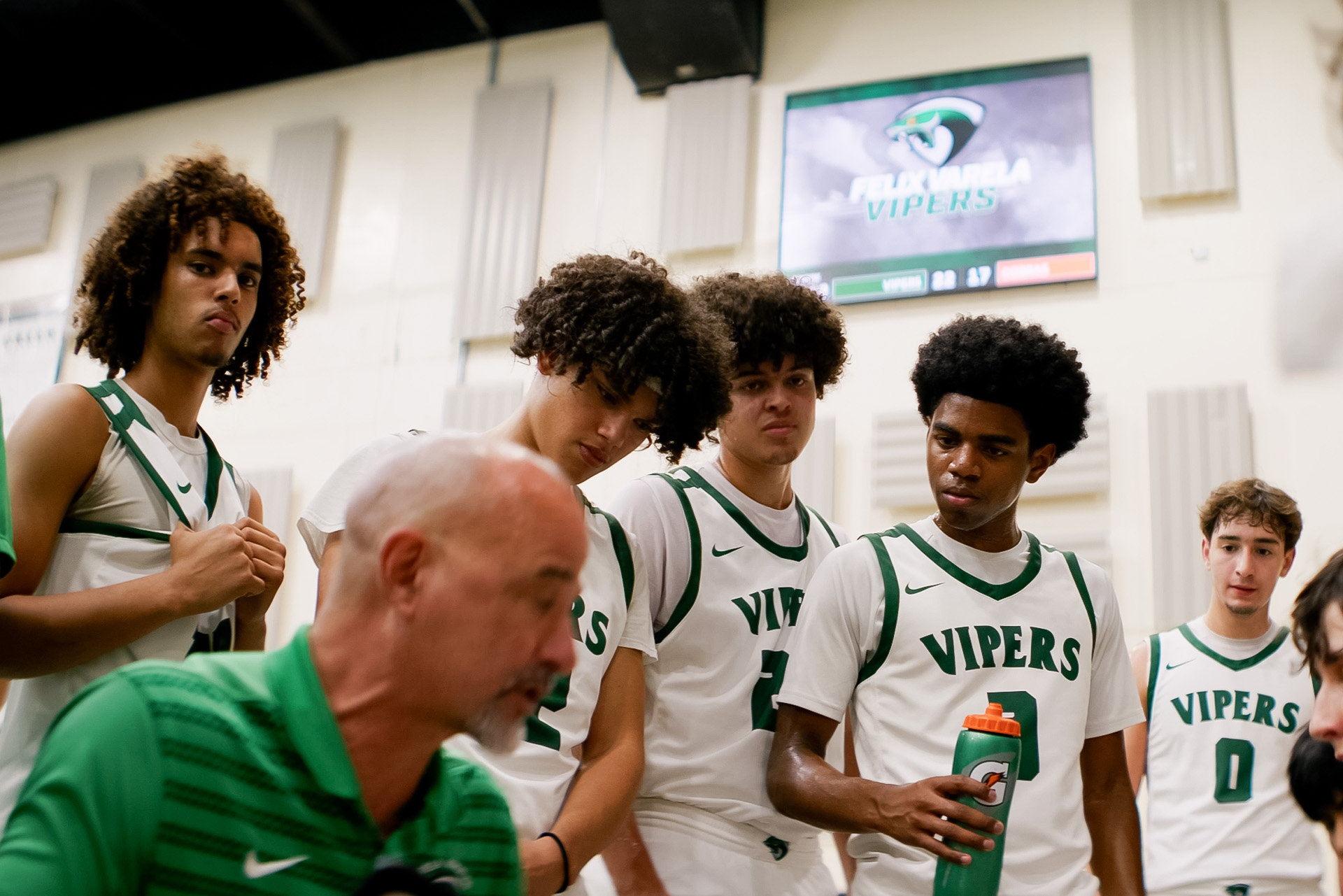 Felix Varela basketball gathers around the coach with live game information visible overhead.