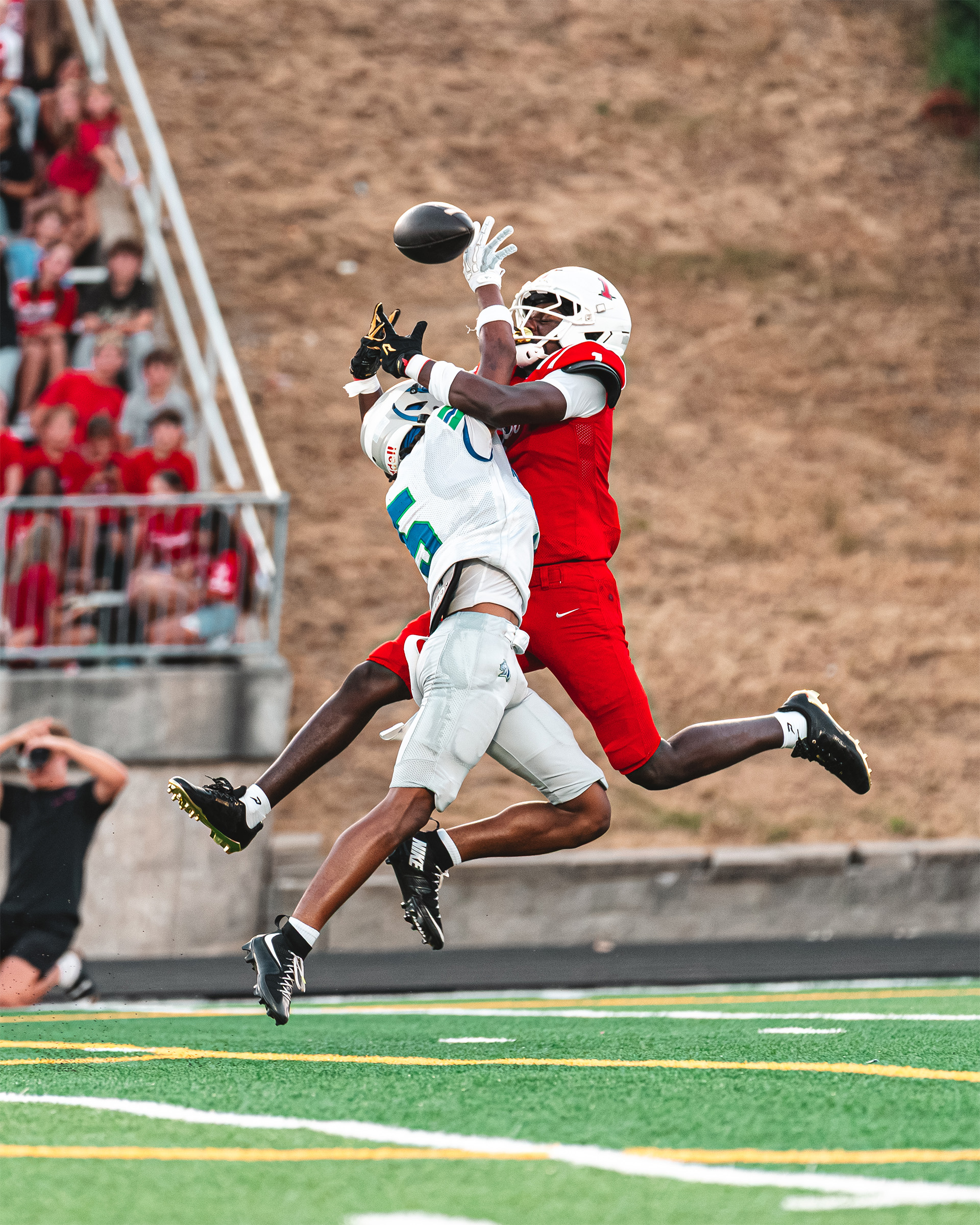 A tightly contested pass sends both sides of the rivalry into the air.