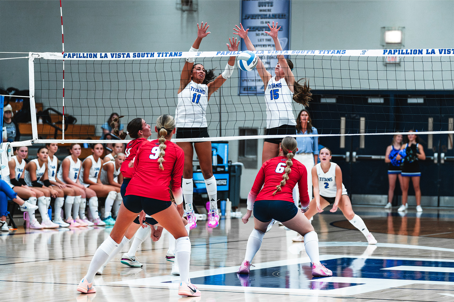 Papillion-La Vista South rises for a double block during a fast-paced volleyball matchup.