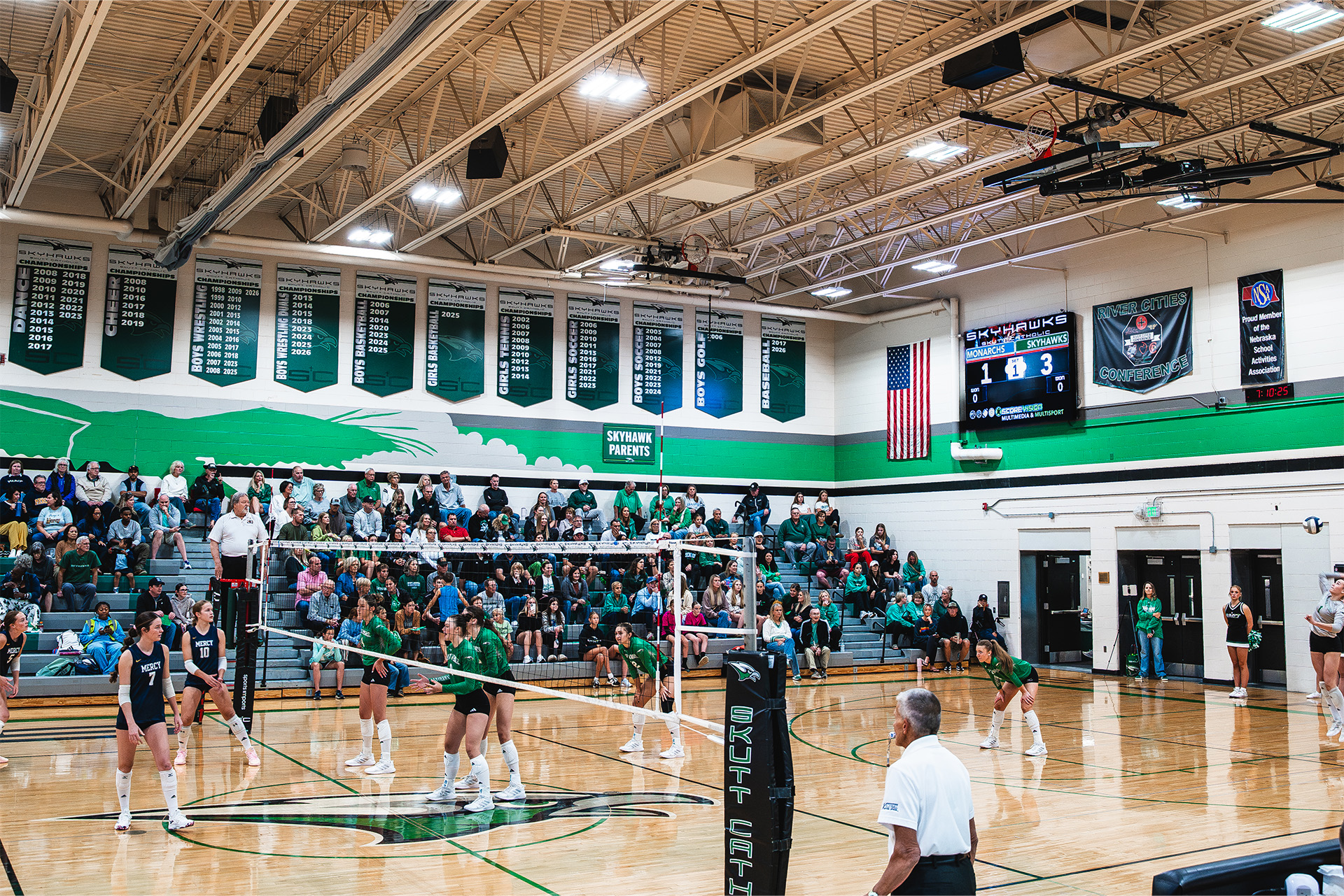 Skutt Catholic volleyball takes the court in a packed home gym.
