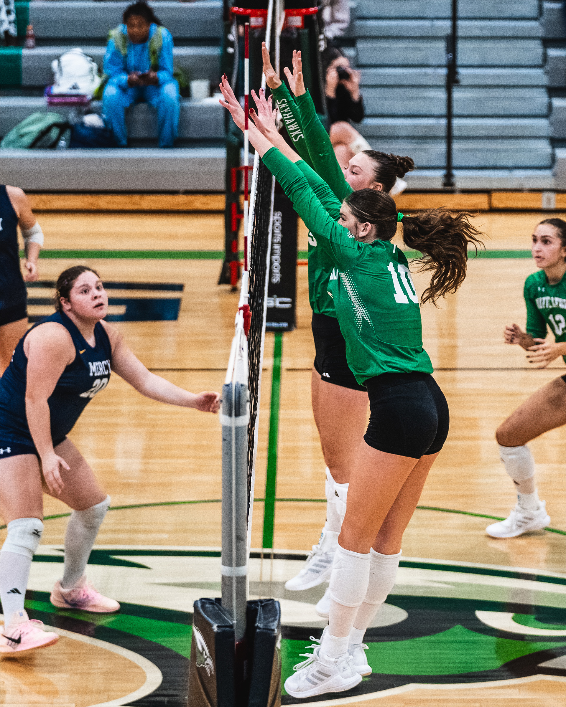 Skutt Catholic defenders rise together for a block at the net.