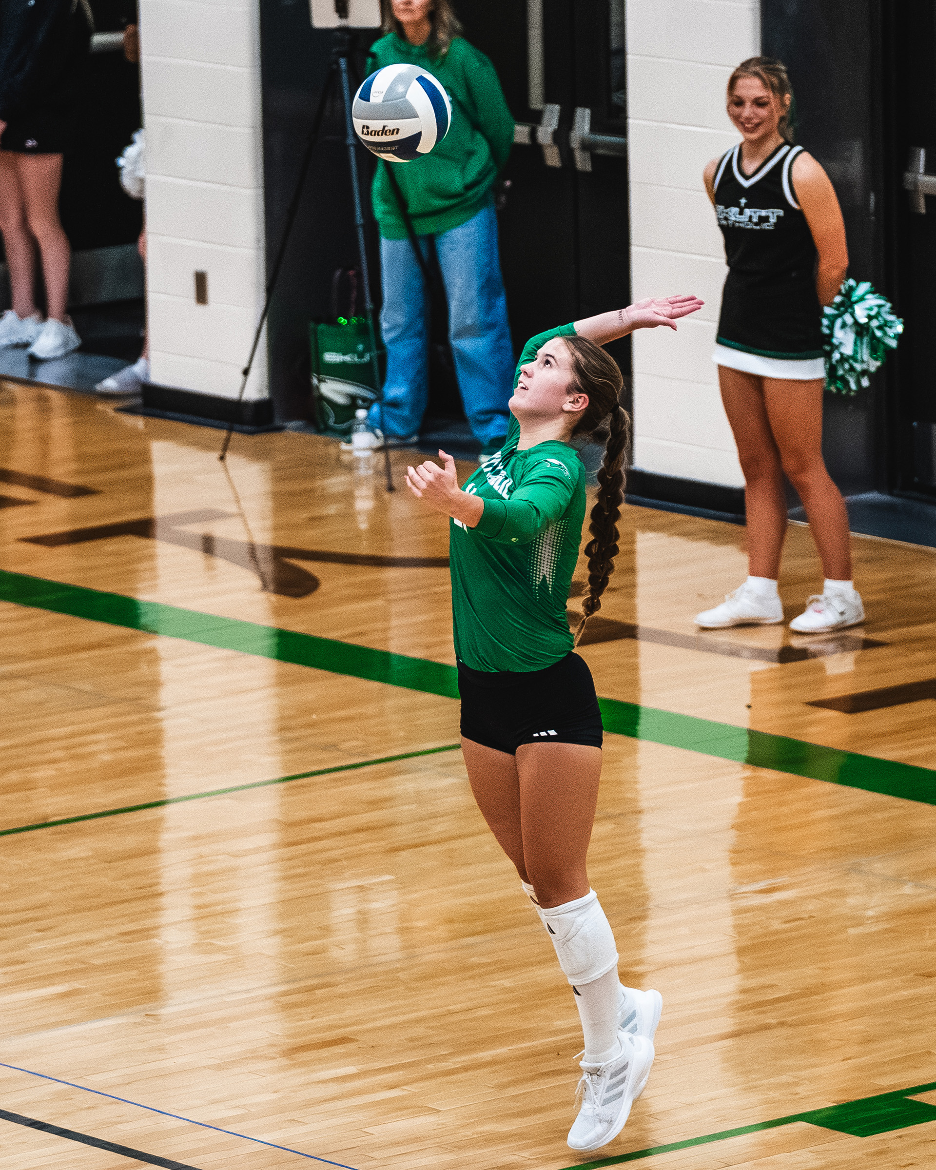 A Skutt Catholic player tosses the ball to begin her serve.