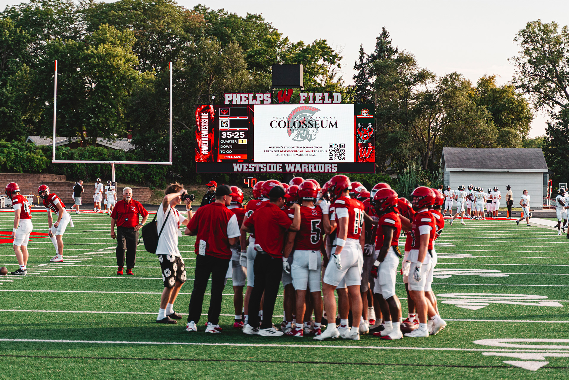 The Westside Warriors gather for a pregame huddle beneath the ScoreVision display at Phelps Field.