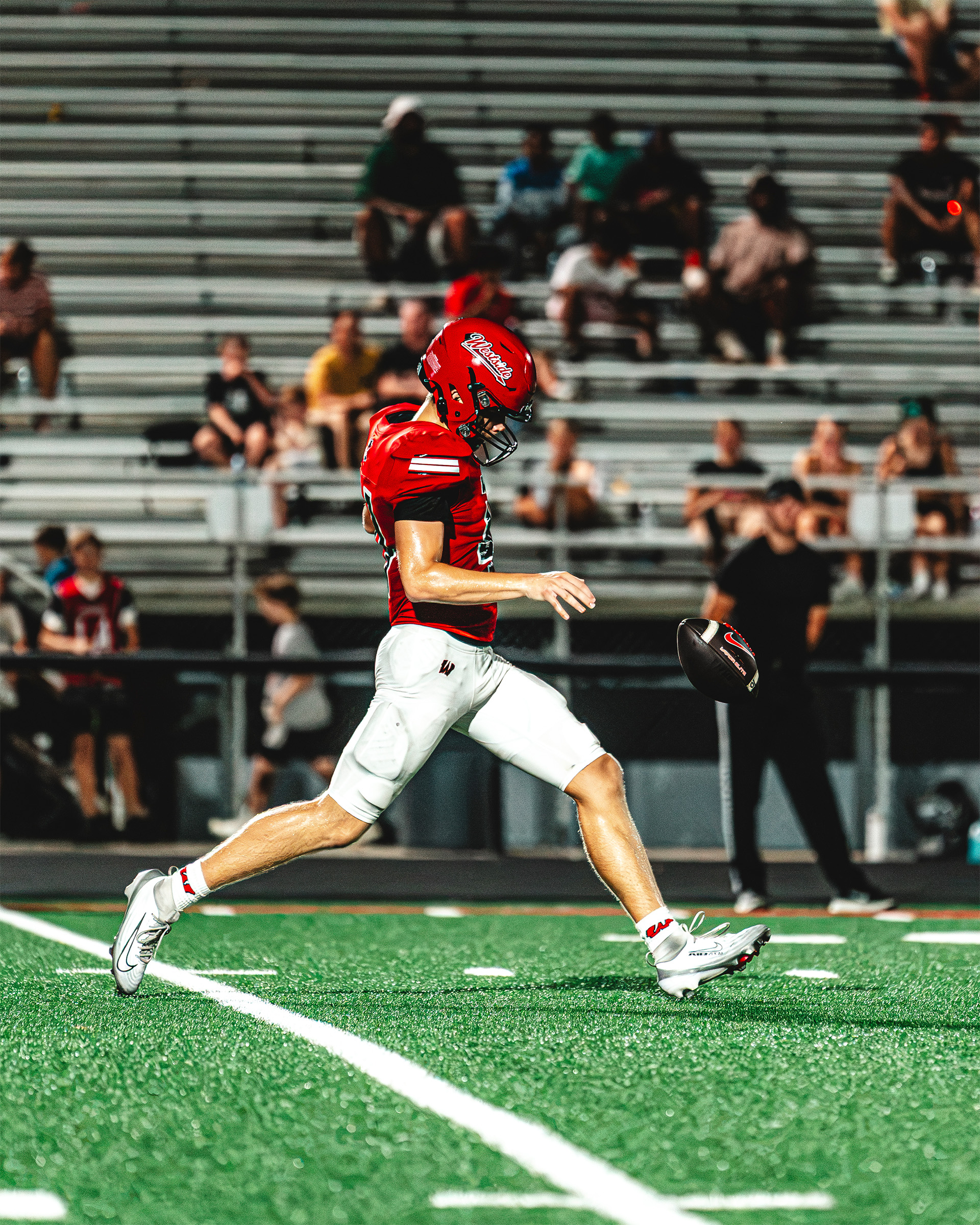 A Westside kicker sends the ball downfield under the stadium lights.