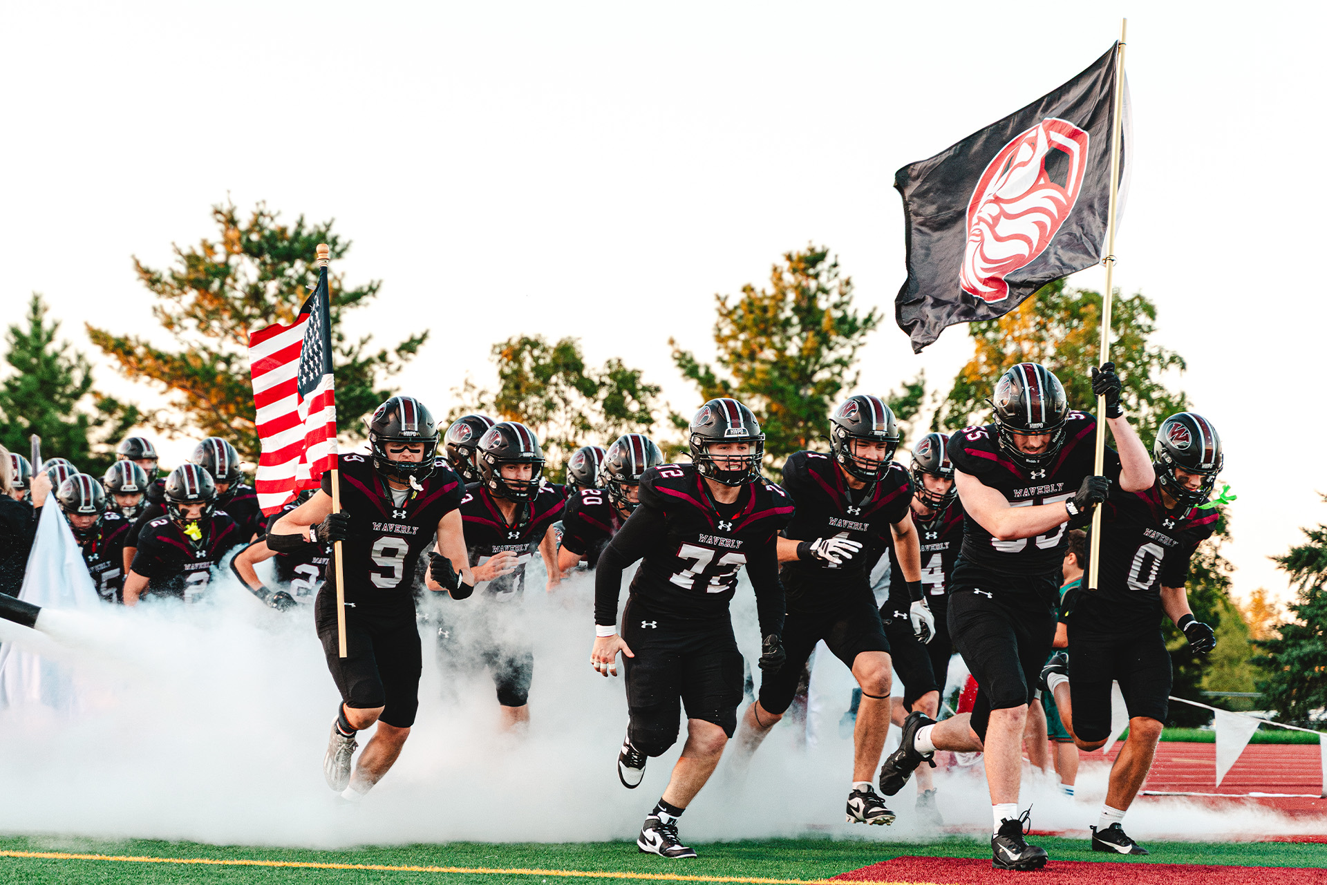 The Waverly Vikings charge through smoke with flags flying as they take the field.